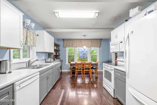 a kitchen with a sink wooden floor dining table chairs and a large window