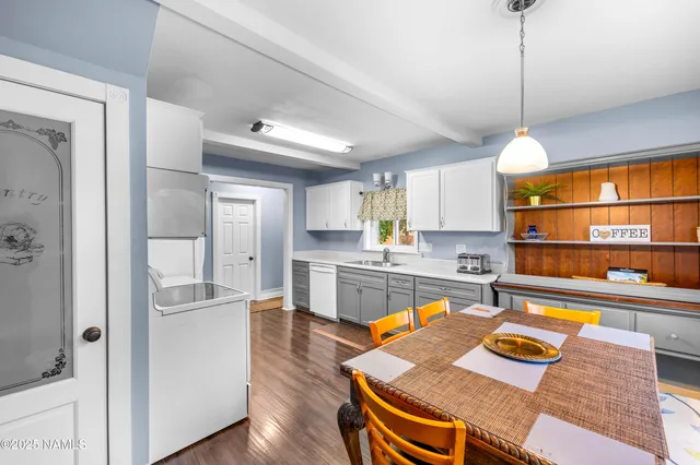 a kitchen island with stainless steel appliances granite countertop a sink and wooden floors