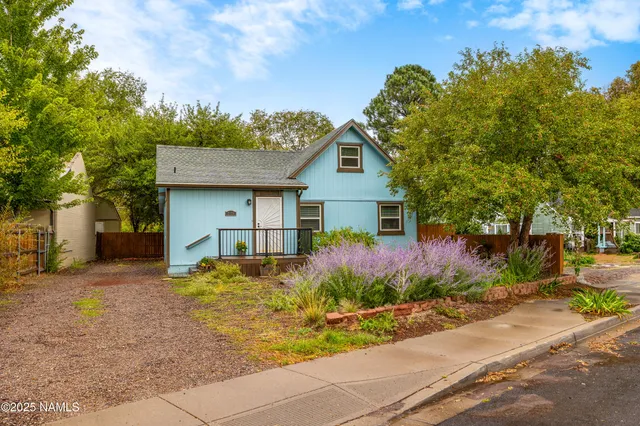 a view of a house with a small yard and large tree