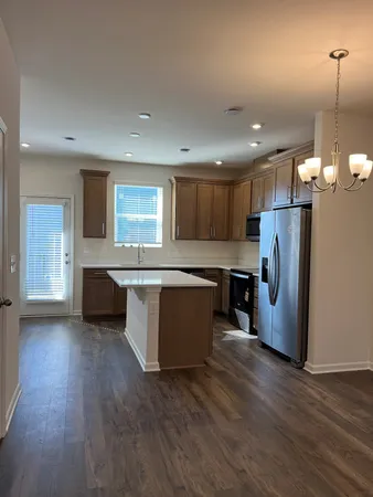 a kitchen with kitchen island granite countertop wooden floors stainless steel appliances a sink and a window