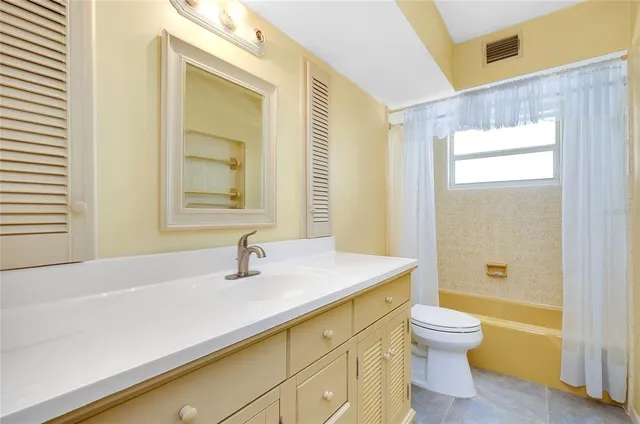 a view of an empty room with a window and a kitchen view