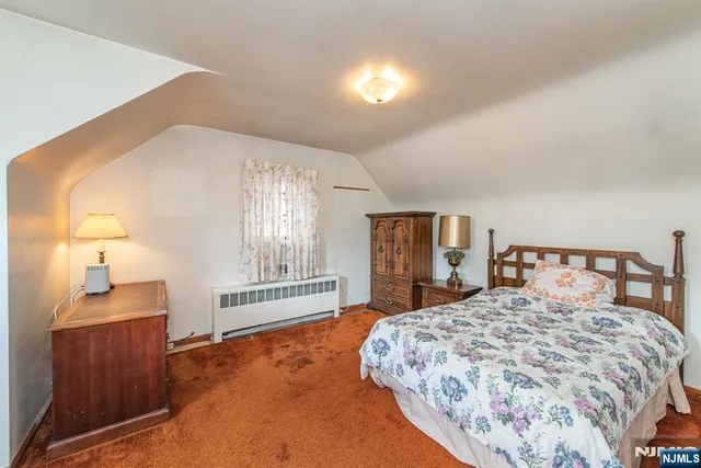 a bedroom with a large bed and a dresser with mirror