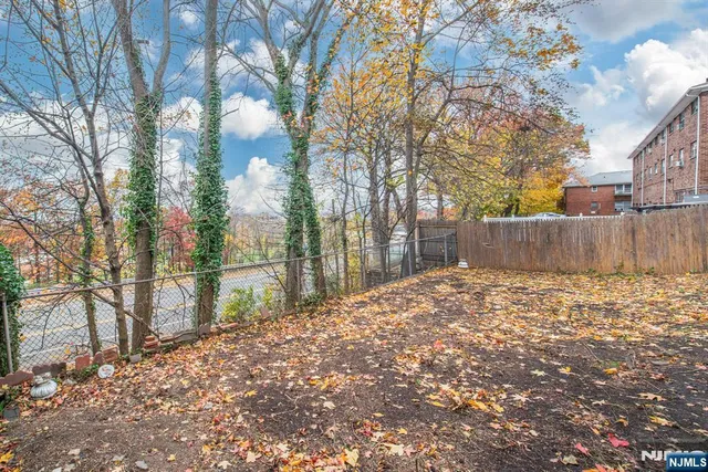 a backyard of a house with large trees and wooden fence