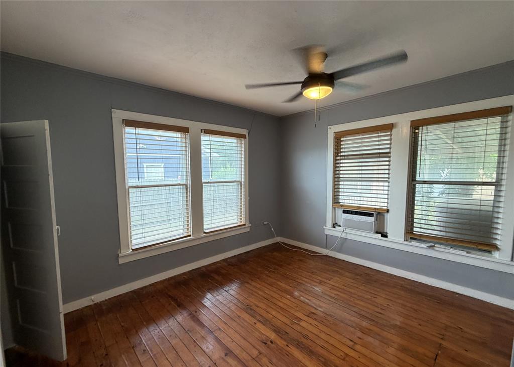 267 North Katy Road Elm Mott, TX 76640 - Photo 6 of 21 Spacious room featuring wood-finish flooring, light grey painted walls, white trim, and two large windows with blinds