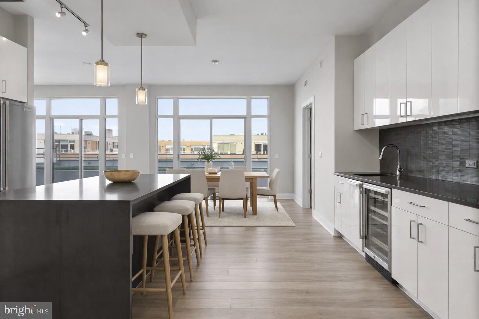 88 V Street Southwest, Unit PH3 Washington, DC 20024 - Photo 3 of 49 a kitchen with stainless steel appliances granite countertop a stove a refrigerator a kitchen island a dining table and chairs with wooden floor