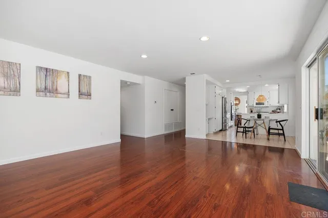 a view of a livingroom with wooden floor and a kitchen