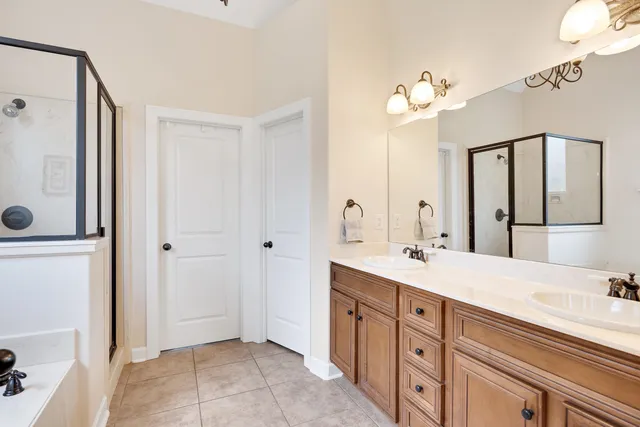 a spacious bathroom with a double vanity sink a mirror and shower