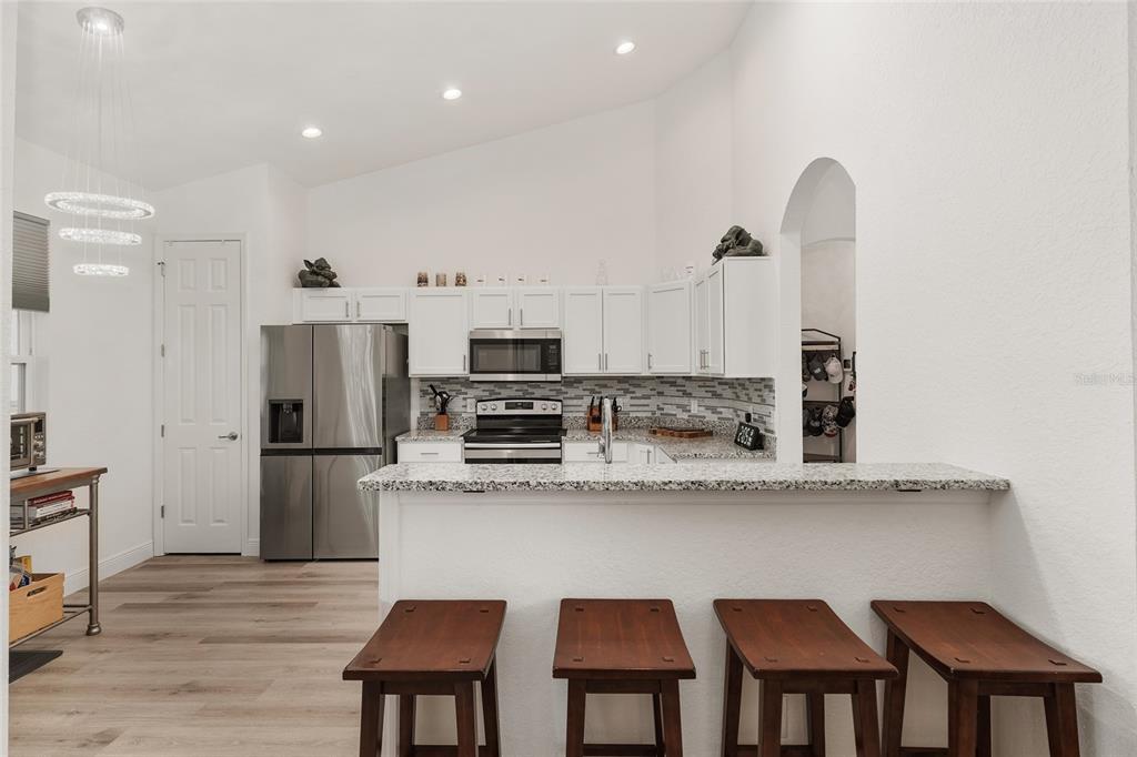 4321 Southwest 106th Place Ocala, FL 34476 - Photo 24 of 82 a kitchen with stainless steel appliances granite countertop a refrigerator a stove top oven a sink dishwasher and white cabinets with wooden floor