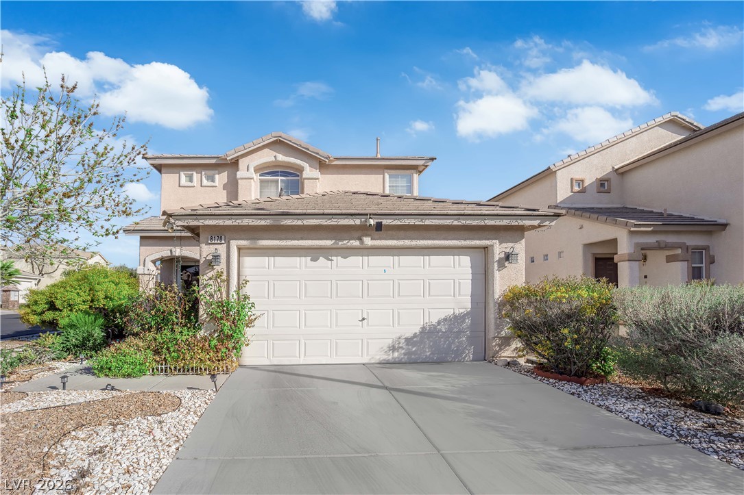 View of front of house with a garage, driveway, and stucco siding