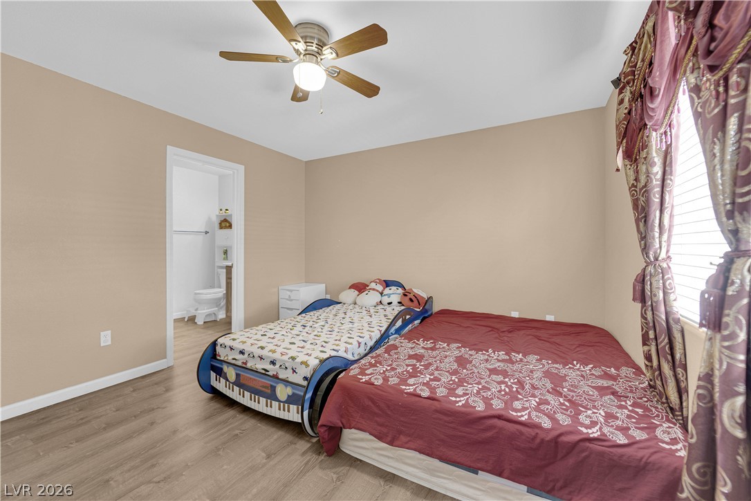 8170 West Festuca Way Las Vegas, NV 89113 - Photo 19 of 29 Bedroom featuring wood finished floors, a ceiling fan, and connected bathroom