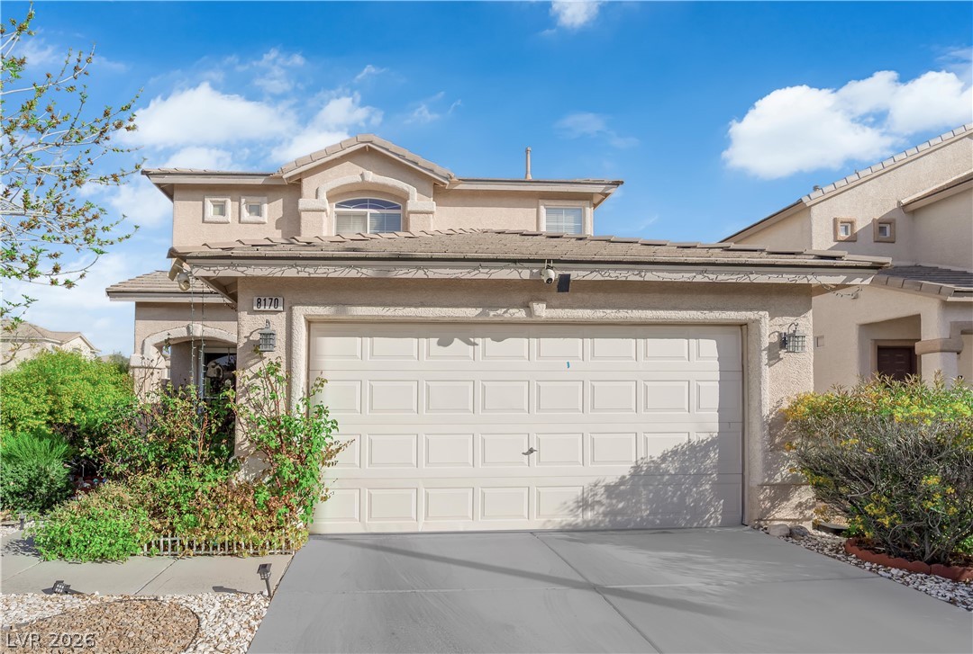 8170 West Festuca Way Las Vegas, NV 89113 - Photo 2 of 29 View of front facade featuring stucco siding, an attached garage, concrete driveway, and a tiled roof