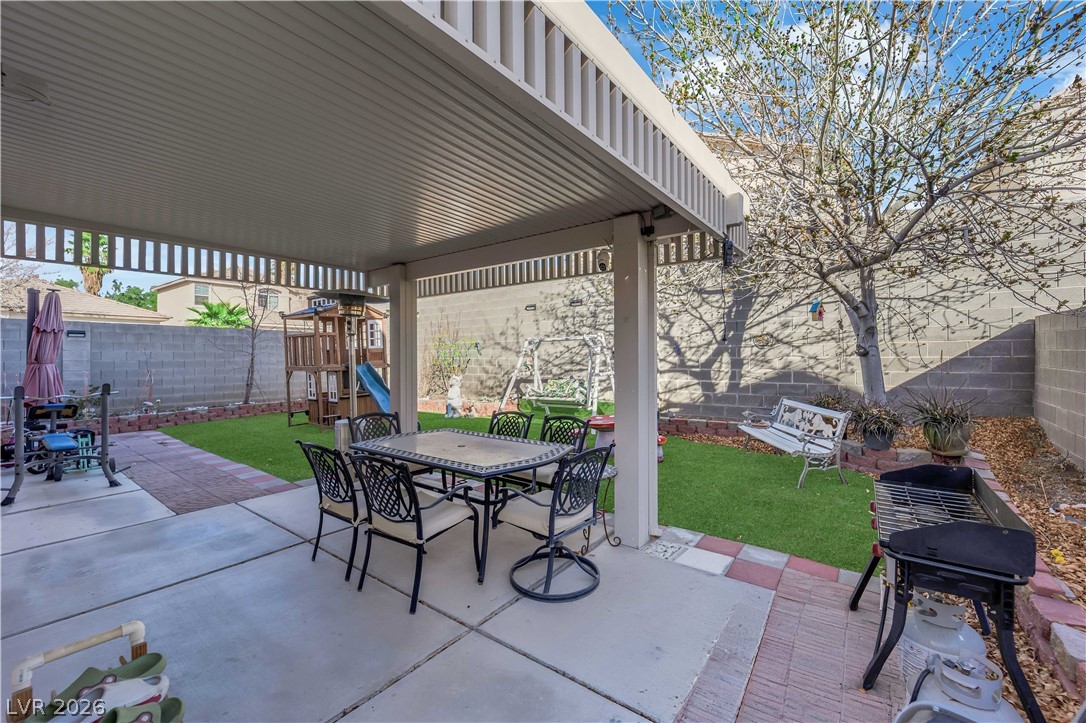 8170 West Festuca Way Las Vegas, NV 89113 - Photo 7 of 29 Fenced backyard featuring outdoor dining space, a patio, a grill, and a playground