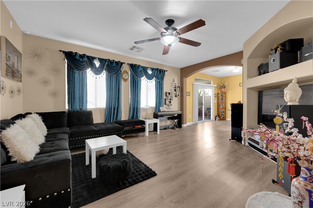 8170 West Festuca Way Las Vegas, NV 89113 - Photo 8 of 29 Living room featuring light wood-style floors, arched walkways, and ceiling fan