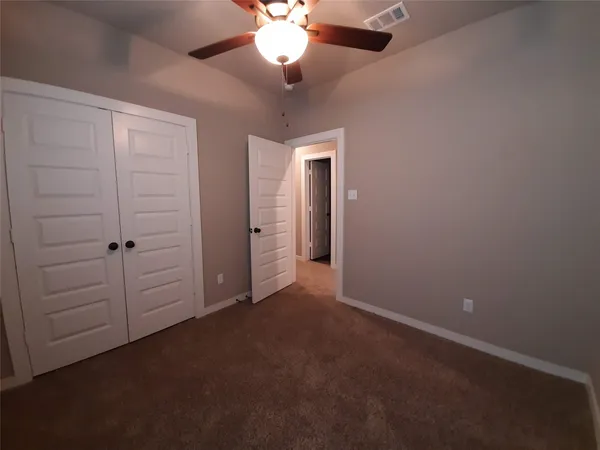 an empty room with closet and a chandelier fan