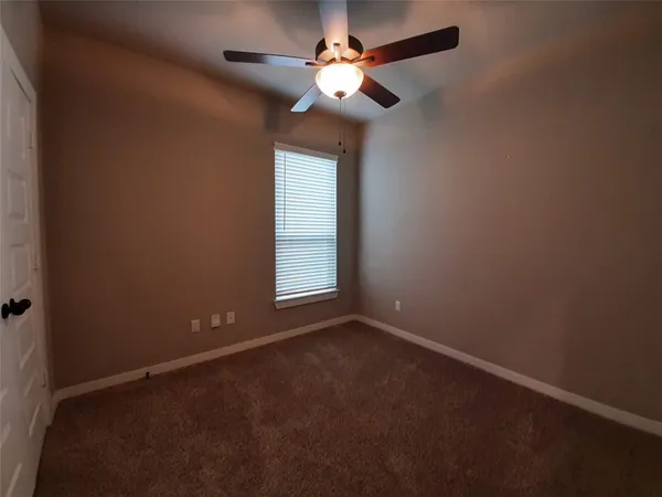 an empty room with a window and a fan