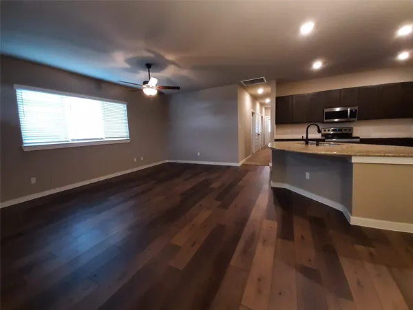 an open kitchen with wooden floor and stainless steel appliances
