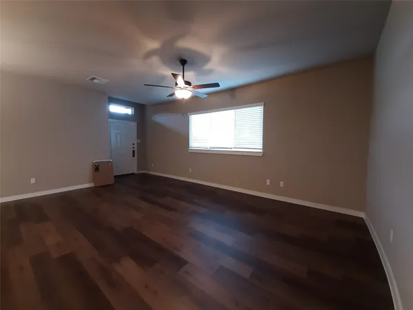 an empty room with wooden floor and ceiling fan