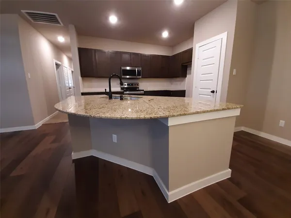 a kitchen with stainless steel appliances granite countertop a sink a microwave counter space and wooden floor