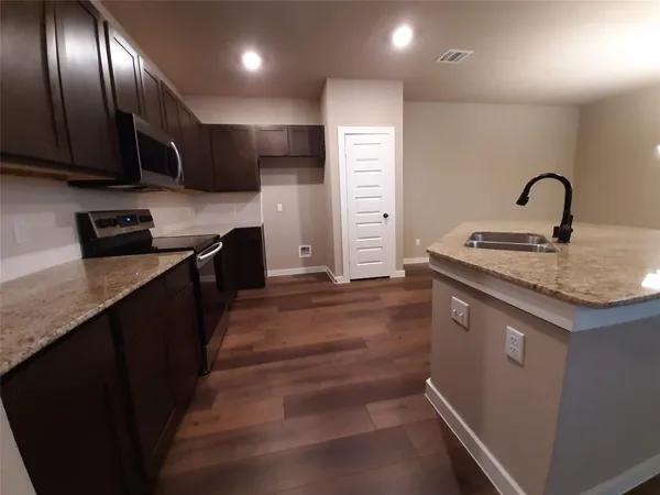 a kitchen with stainless steel appliances granite countertop a sink a stove and a refrigerator