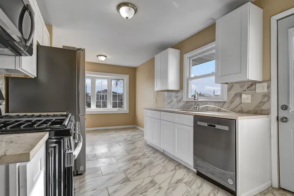 a kitchen with granite countertop a stove a sink and a refrigerator