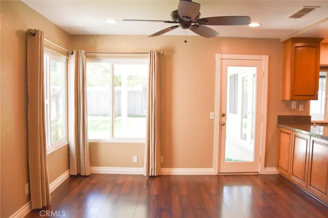 an empty room with wooden floor fan and windows