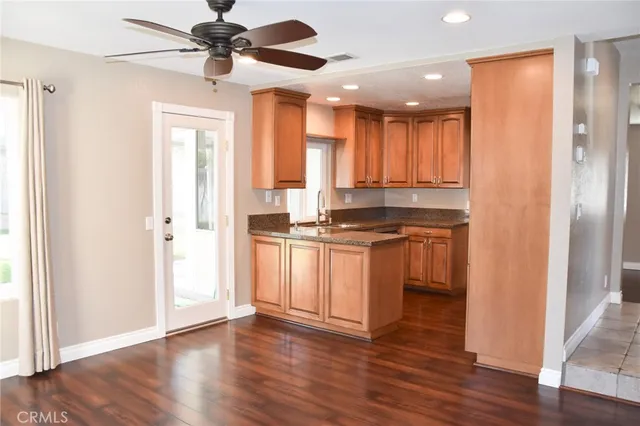 a kitchen with kitchen island granite countertop a refrigerator a sink and white cabinets