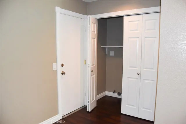 a view of an empty room with wooden floor and closet