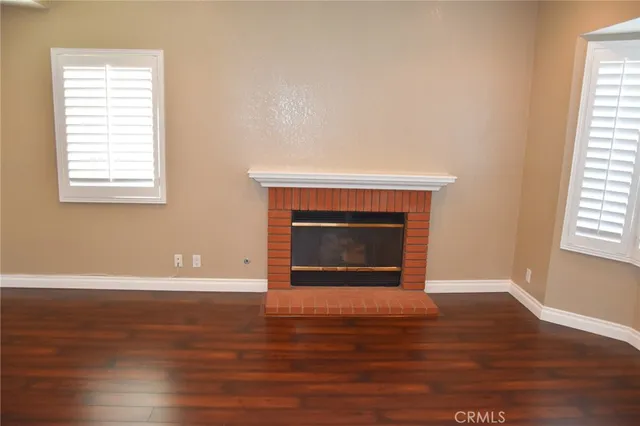 a view of an empty room with wooden floor and a fireplace