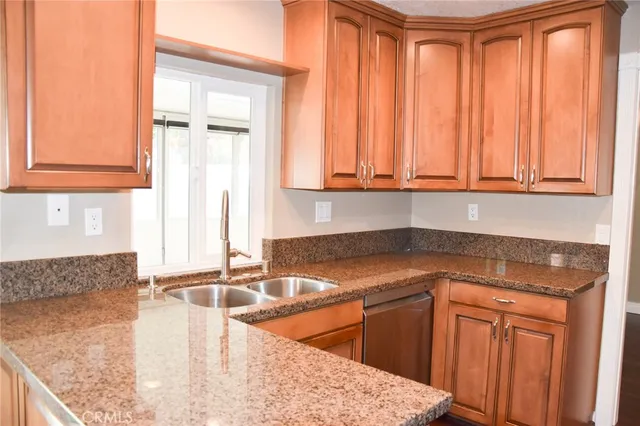a kitchen with granite countertop a sink a stove and cabinets