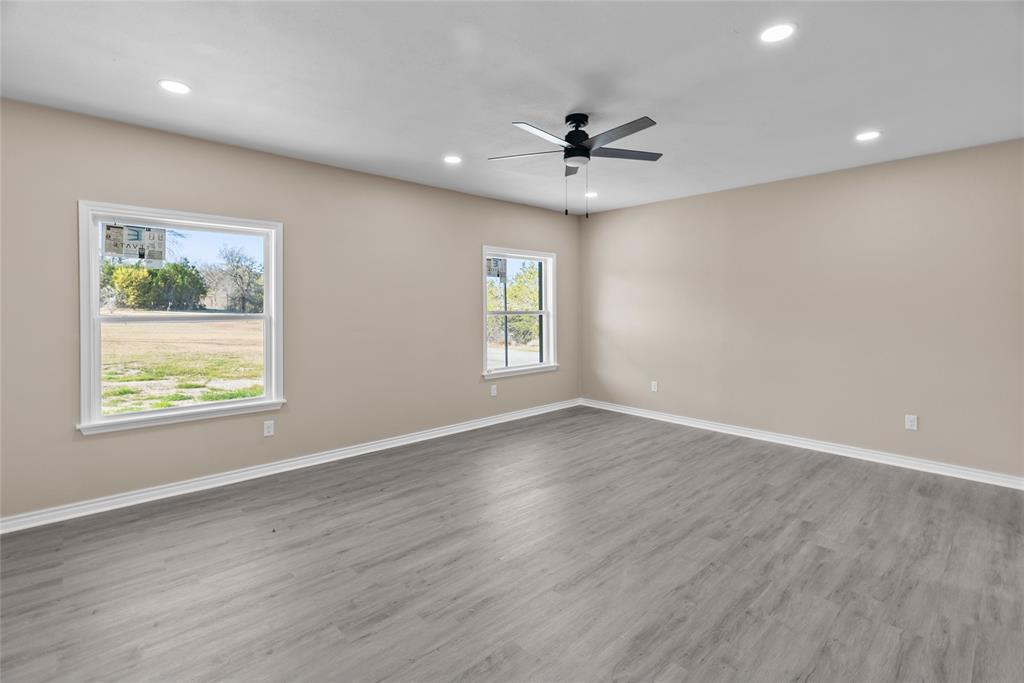 170 High Ridge Drive Azle, TX 76020 - Photo 11 of 36 an empty room with wooden floor chandelier fan and windows