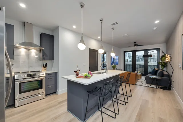 a view of a kitchen with kitchen island a stove a counter space a sink and a living room view