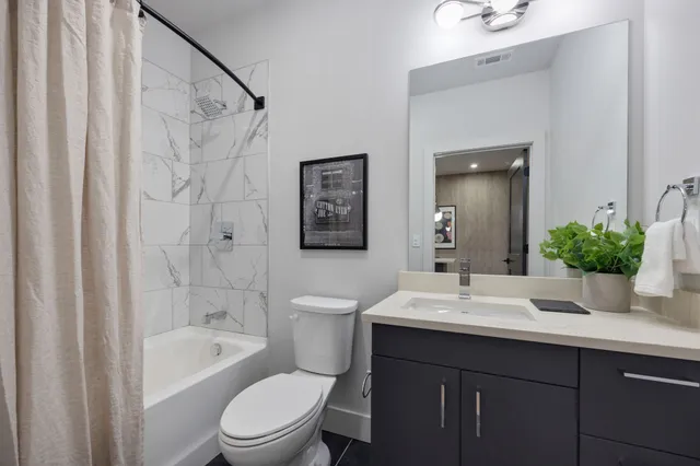 a bathroom with a sink a toilet a mirror a bathtub and shower