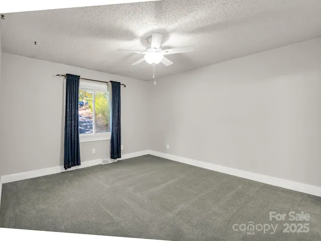 an empty room with fan and windows