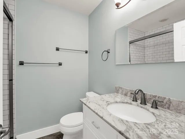 a bathroom with a granite countertop sink toilet and a mirror