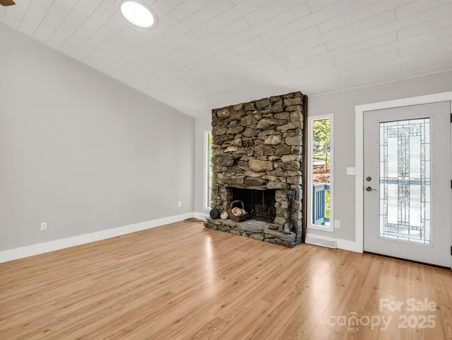 an empty room with wooden floor fireplace and windows