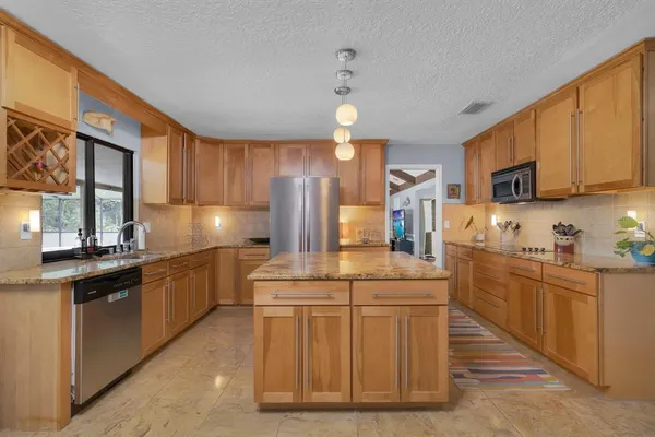 a kitchen with stainless steel appliances granite countertop a refrigerator a stove and a sink