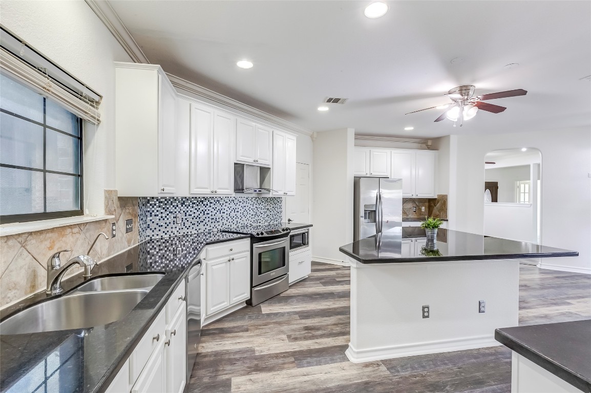 2310 McKendrick Drive Cedar Park, TX 78613 - Photo 14 of 32 a kitchen with granite countertop kitchen island a counter space a sink stainless steel appliances and windows
