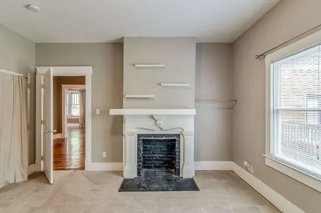 an empty room with windows and fireplace