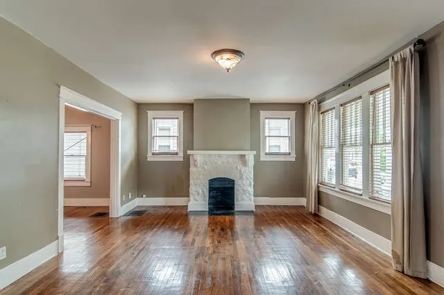 wooden floor fireplace and windows in an empty room