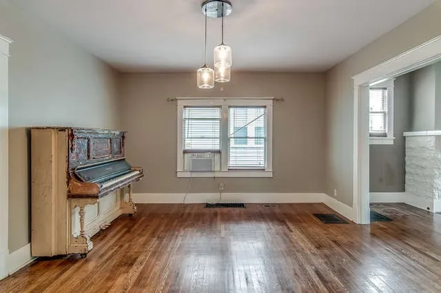 an empty room with wooden floor cabinet and windows