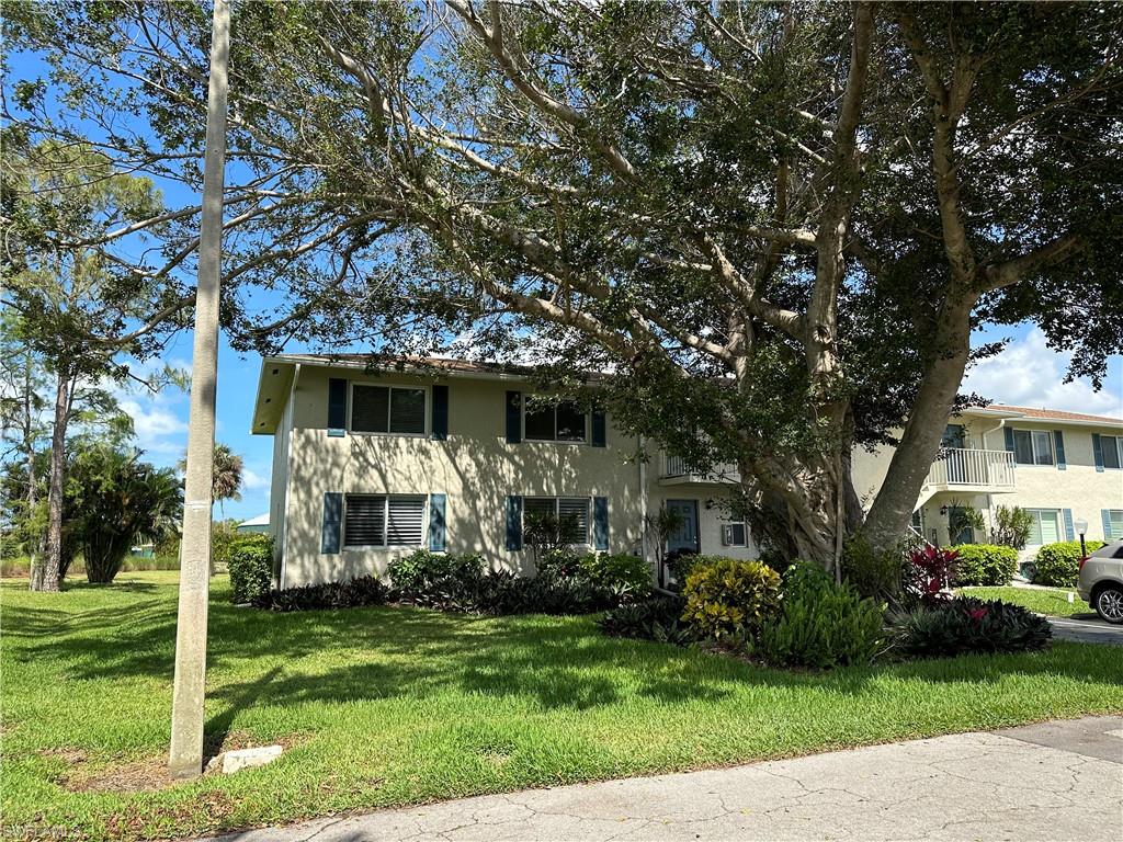 231 Memory Lane, Unit 3 Naples, FL 34112 - Photo 2 of 27 a front view of a house with a yard table and chairs