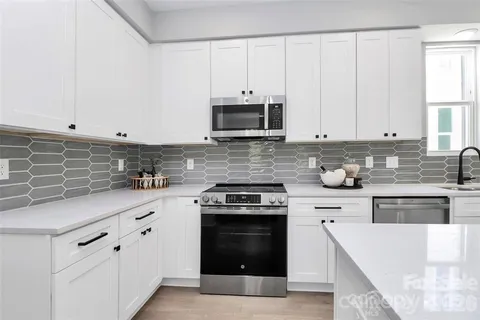 a kitchen with granite countertop white cabinets and stainless steel appliances