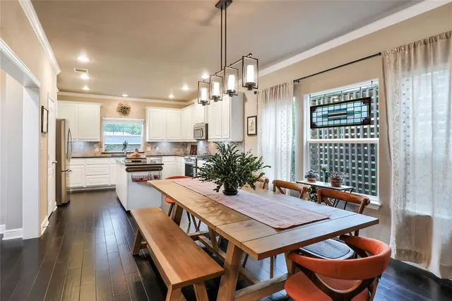 a dining room with stainless steel appliances a table chairs and kitchen view