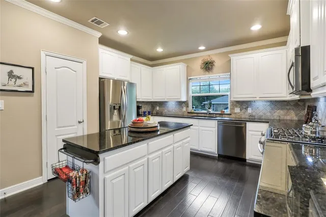 a kitchen with kitchen island granite countertop a sink cabinets and stainless steel appliances