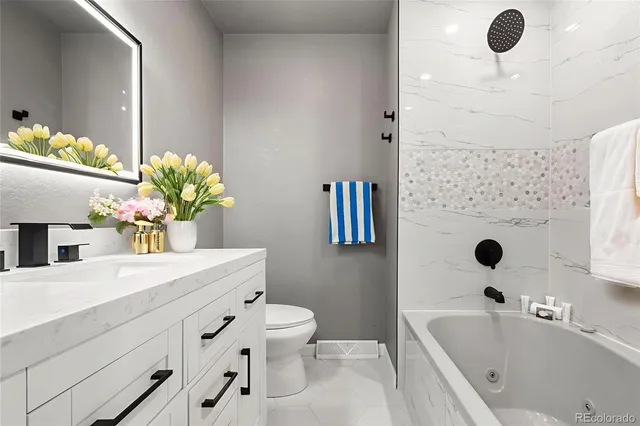 a bathroom with a bathtub sink vanity mirror and toilet