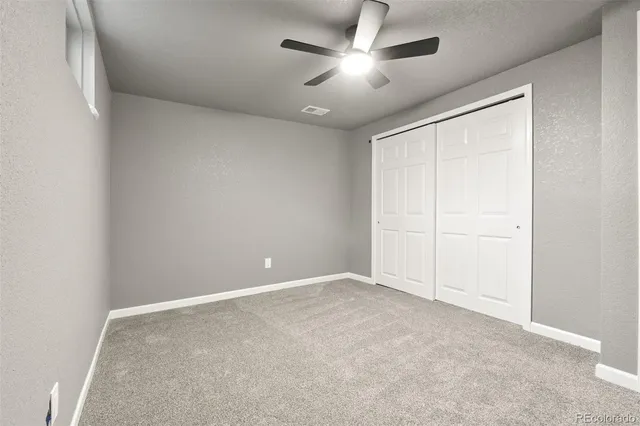 an empty room with a ceiling fan and window