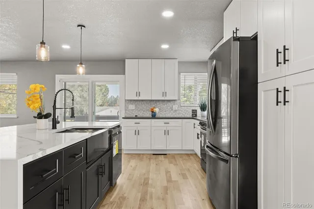 a kitchen with stainless steel appliances granite countertop a refrigerator sink and white cabinets