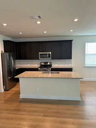a view of kitchen with stainless steel appliances granite countertop a stove a sink a refrigerator and a microwave