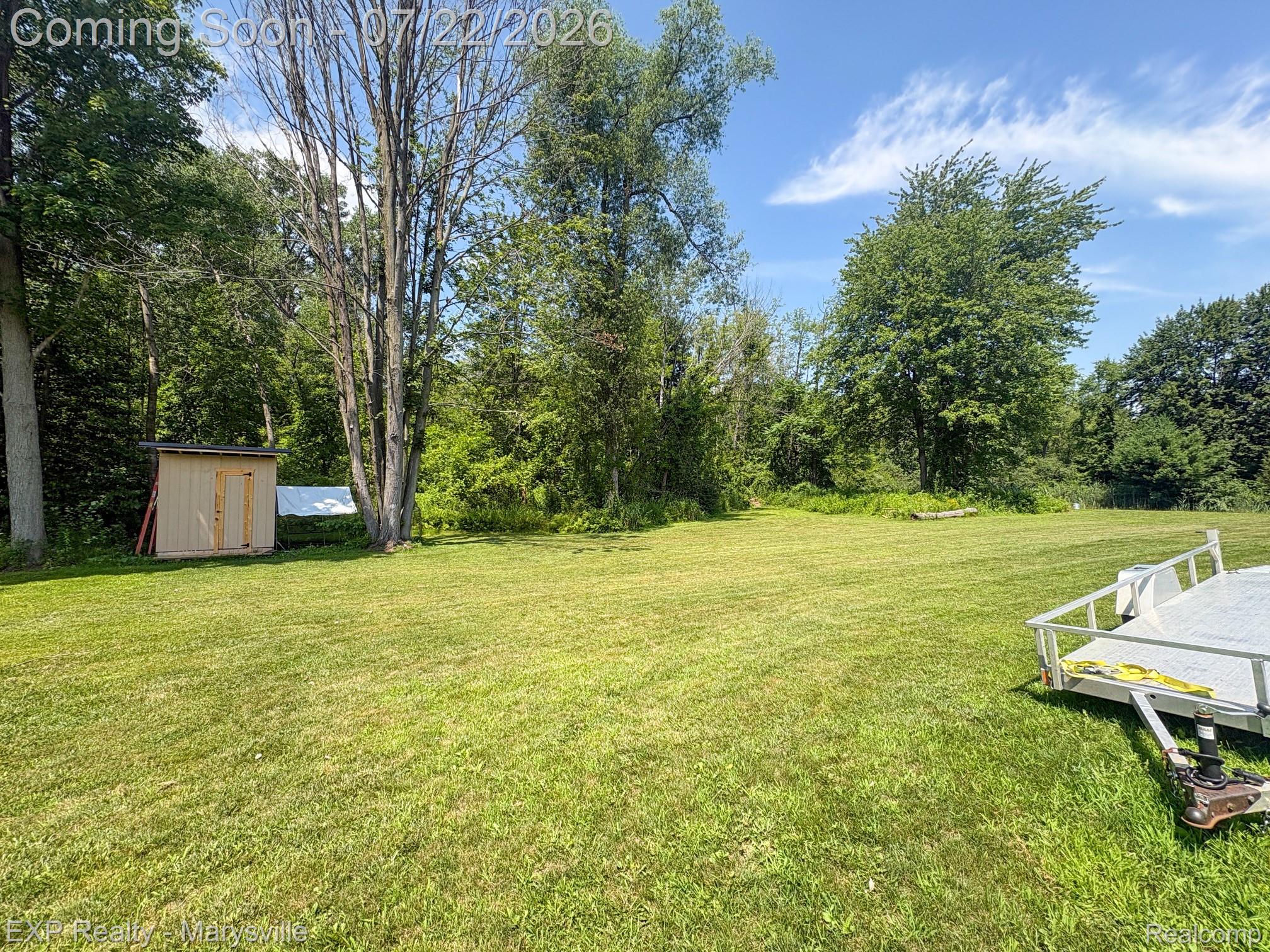 2601 Beach Road Port Huron, MI 48060 - Photo 4 of 34 Expansive grassy outdoor space featuring a utilitarian shed, mature trees, and a clear sky