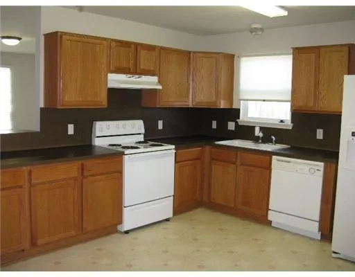 a kitchen with granite countertop white cabinets sink and white appliances